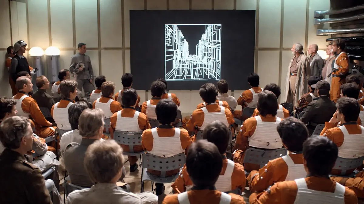 Rebel pilots in orange flight suits seated in a briefing room, watching a glowing battle station schematic projected on a screen as commanders look on